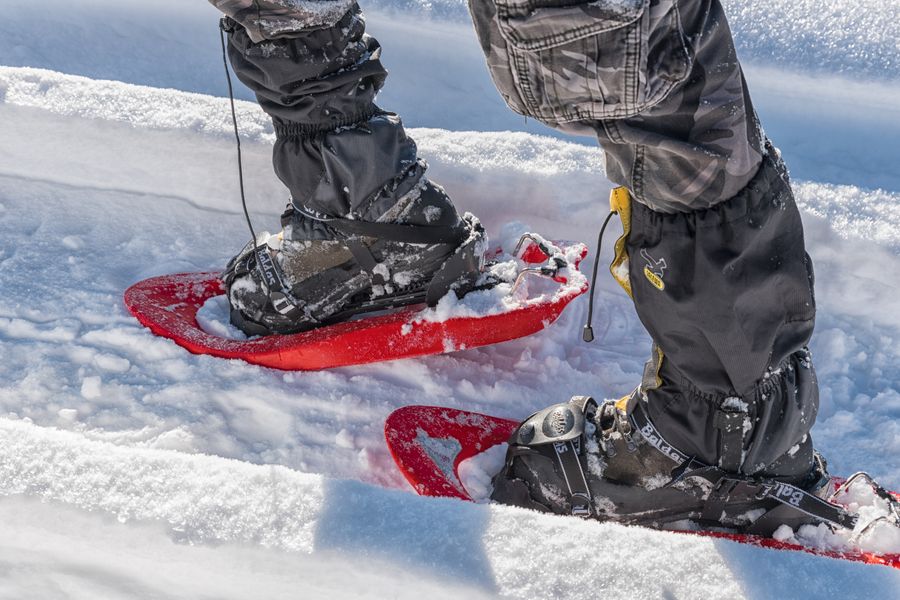 Gros plan de chaussures de randonnée équipées de raquettes à neige rouges dans la neige fraîche