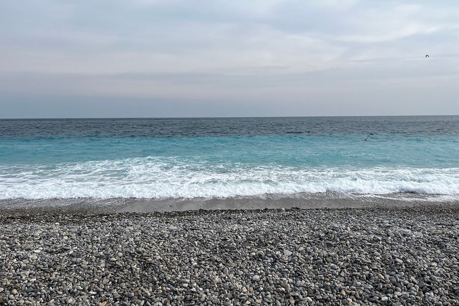 Plage de galets de la promenade des Anglais à Nice, vagues et ciel bleu
